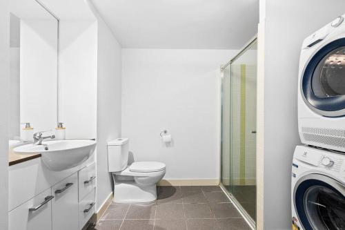 a bathroom with a toilet and a washer and dryer at 37F Brisbane CBD Apartment with City Views and Pool in Brisbane