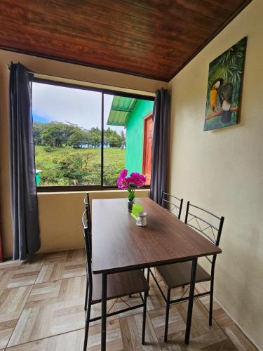 a dining room with a table and a large window at Aves del Paraíso in Tilarán