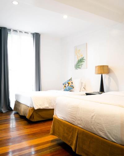 two beds in a hotel room with wood floors at 87 Guesthouse in Baguio