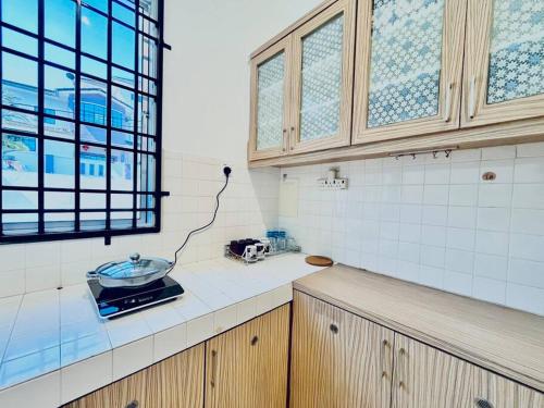eine Küche mit weiß gefliesten Wänden und einem Fenster in der Unterkunft Gioia2Home 5 mins to Taiping/Kamunting in Taiping