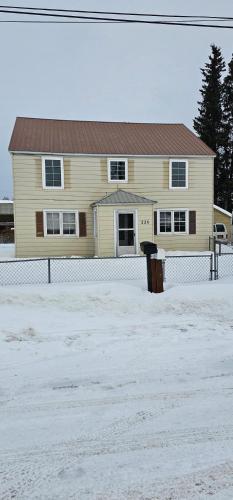 a yellow house with a fence in the snow at Downtown Aurora house #1 in Fairbanks