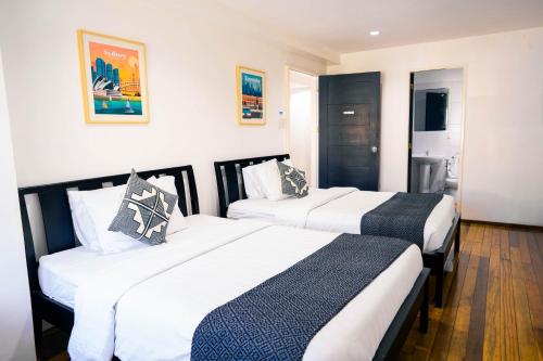 two beds in a hotel room with white walls at 87 Guesthouse in Baguio