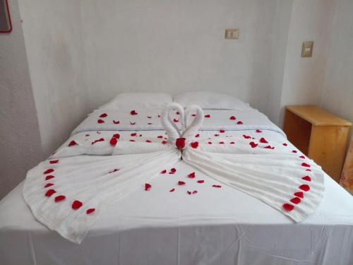 uma cama branca com corações vermelhos em POSADA DOÑA ELENA LA COMADRONA em San Juan La Laguna
