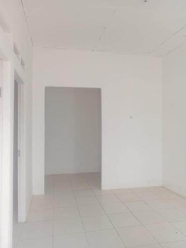 Permata Homestay في كراوانغ: غرفة فارغة بجدران بيضاء وأرضية من البلاط الأبيض