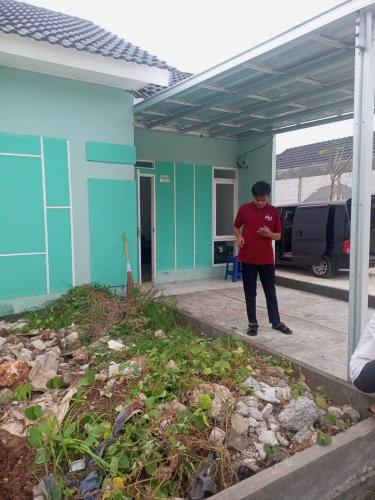 a man standing in front of a blue house at Permata Homestay in Karawang