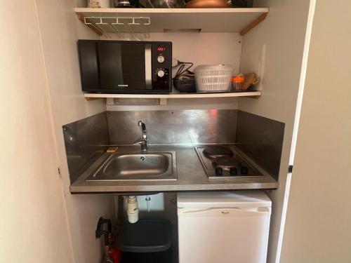 une petite cuisine avec un évier et un micro-ondes dans l'établissement Studio 3 pers, Wi-Fi, Centre Avoriaz - FR-1-314-281, à Morzine