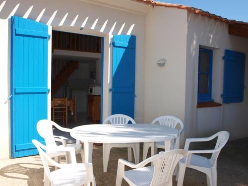une table blanche, des chaises blanches et une porte bleue dans l'établissement Maison à Saint-Jean-de-Monts avec Piscine Chauffée, proche Plage et Commerces - FR-1-323-377, à Saint-Jean-de-Monts