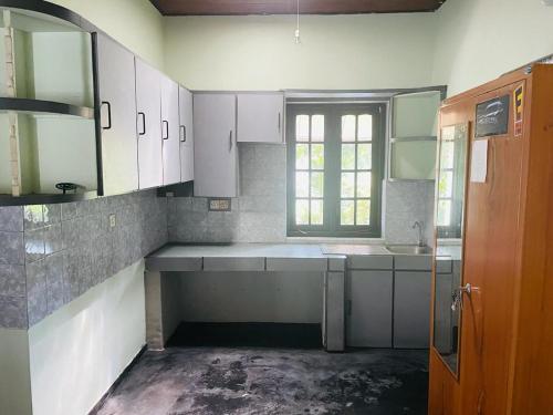 an empty kitchen with white cabinets and a window at Galle Side HomeStay in Galle