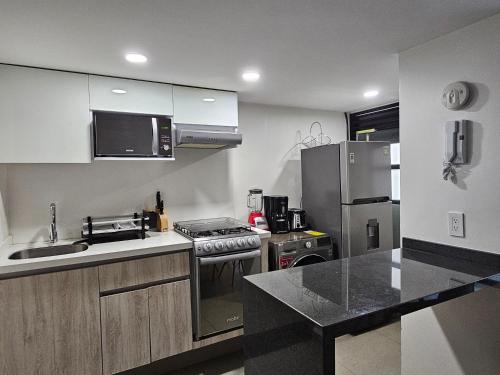 a kitchen with a stove and a stainless steel refrigerator at NSI Alameda Park Humboldt Mexico City in Mexico City