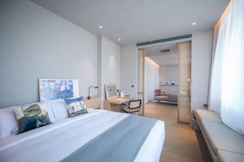 um quarto com uma grande cama branca e uma secretária em Read and Rest Hotel em Pequim