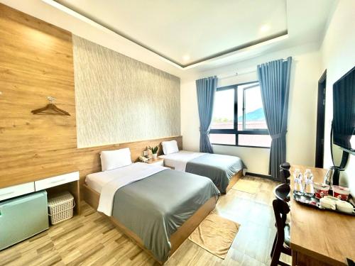 バオロクにあるHotel Hoa Nắngのベッド2台とテレビが備わるホテルルームです。