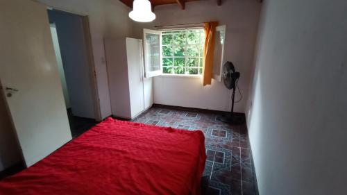 1 dormitorio con cama roja y ventana en quinta el ensueño en General Rodríguez