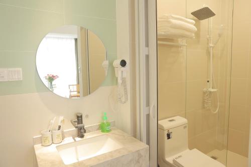 a bathroom with a sink and a toilet and a mirror at 三亚豪晟珠崖民宿(海棠湾免税城店) in Sanya