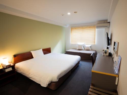 a bedroom with a bed and a desk and a television at You Style Hotel MARINE in Kagoshima