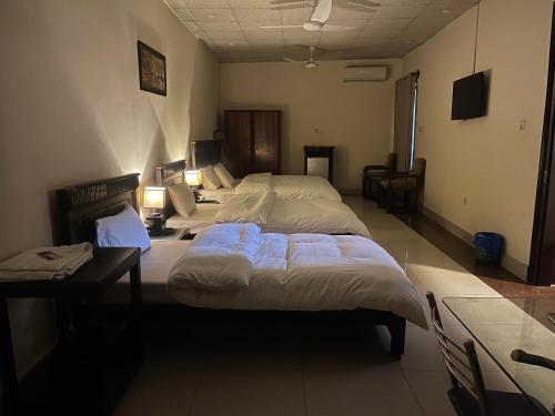 a bedroom with two beds and a desk and a bed at Crown Castle Peshawar in Peshawar