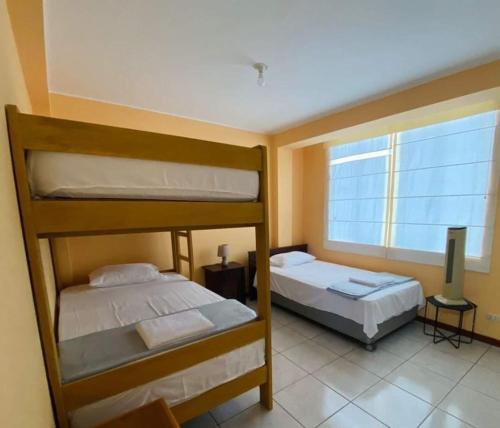 Ce dortoir comprend 2 lits superposés et une fenêtre. dans l'établissement CASA DE PLAYA CON PISCINA PUNTA NEGRA, à Punta Hermosa