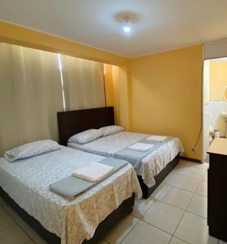 - 2 lits dans une chambre aux murs jaunes dans l'établissement CASA DE PLAYA CON PISCINA PUNTA NEGRA, à Punta Hermosa