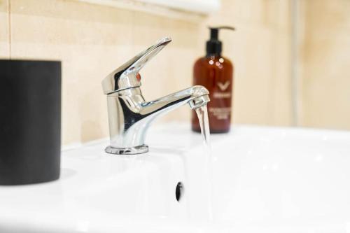 a sink with a faucet and a bottle of soap at Modern Arcadian Center Apartment By Azura Nights in Birmingham