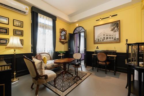 a living room with yellow walls and a table and chairs at DE Phanakron Boutique Hotel in Bangkok