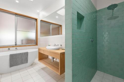 a bathroom with a tub and a sink and a mirror at Lonnie Getaway in Point Lonsdale