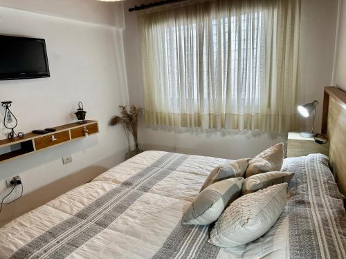 a bedroom with a bed with pillows and a television at Sol y Vida in Godoy Cruz