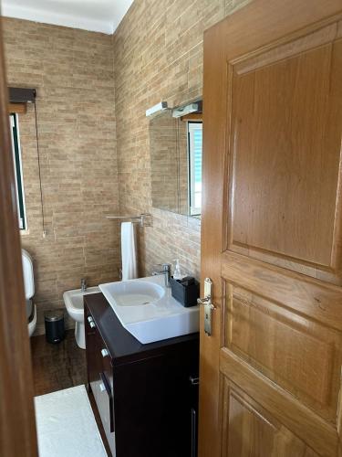 a bathroom with a sink and a wooden door at Peaceful Retreat Leiria in Marinha Grande