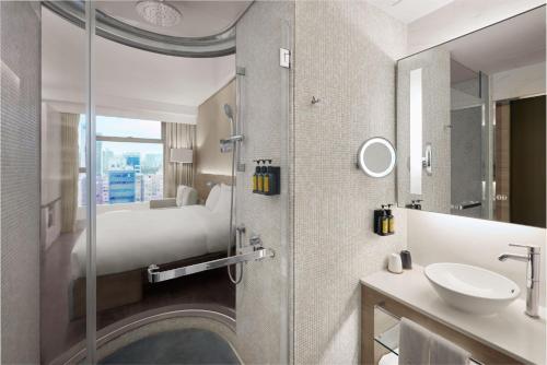 bagno con letto, lavandino e specchio di Lodgewood by Nina Hospitality Mong Kok a Hong Kong