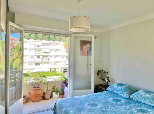 une chambre avec un lit bleu et une fenêtre dans l'établissement Palm Beach apartment, à Cannes
