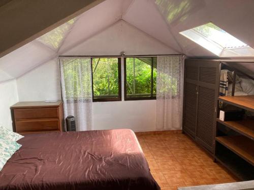 an attic bedroom with a bed and windows at Shiozaki in Bajos del Toro