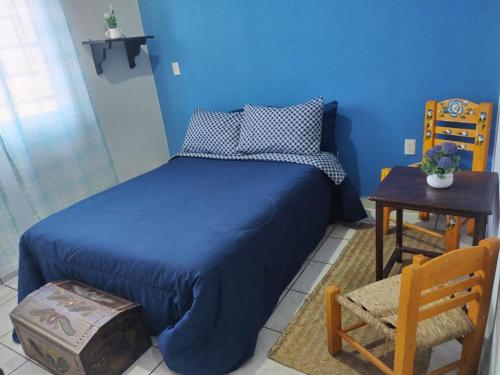 ein blaues Schlafzimmer mit einem Bett, einem Tisch und einem Stuhl in der Unterkunft Departamento centrico in San Juan del Río