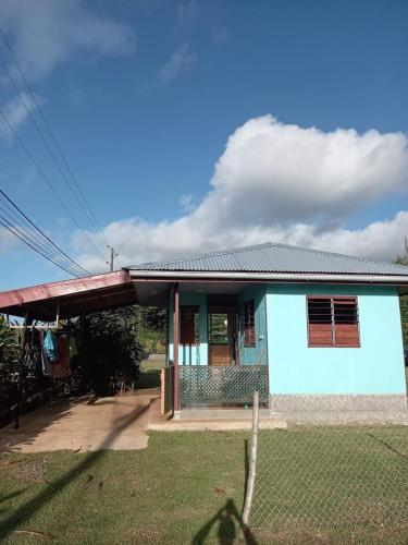 niebieski dom z płotem przed nim w obiekcie Natura Lodge Huahine w mieście Puahua