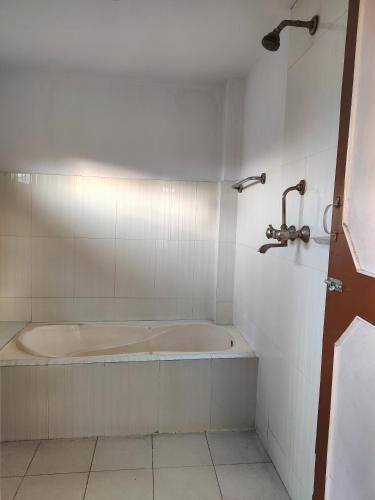 a bath tub in a white tiled bathroom at Family Peace House, Kathmandu in Kathmandu