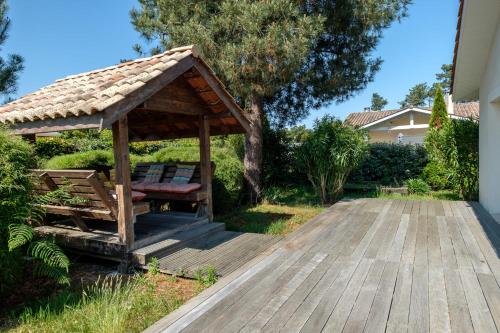 cenador de madera con banco en la cubierta en Magnifique Villa Avec Jardin Proche De La Plage, en Arès