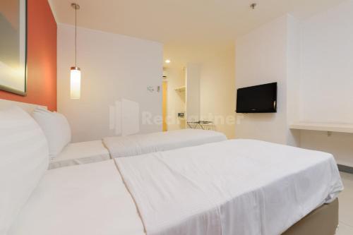 two beds in a white room with a tv at NamRoom Hotel Glodok RedPartner in Jakarta