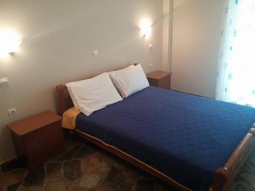 a bedroom with a bed with blue sheets and white pillows at Holiday Tolofona Beach in Eratini