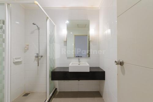 a white bathroom with a sink and a shower at NamRoom Hotel Glodok RedPartner in Jakarta