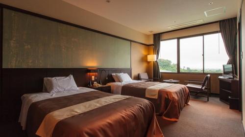 ein Hotelzimmer mit zwei Betten und einem großen Fenster in der Unterkunft Hotel Ryutouen in Saga