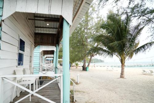 a building on the beach with a palm tree at Sandy Beach Bungalows By EHM in Koh Rong Sanloem