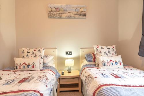 a bedroom with two beds and a table with a lamp at 31 Ocean Terrace with Hot Tub Available to Hire in Woolacombe