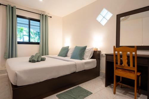 a bedroom with a bed with a desk and a chair at Lanta School Beach Resort in Phra Ae beach