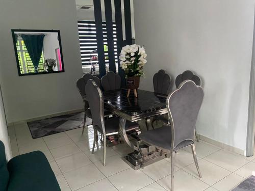 uma mesa de jantar com cadeiras e um vaso de flores em Creatills luxury homestay Kulim & hi-tech em Kulim