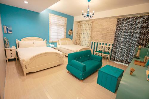 a blue bedroom with two beds and a blue chair at Lamanca in Hualien City