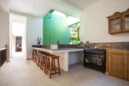 a kitchen with a stove and a counter with stools at Barefoot Bungalow Hikka in Hikkaduwa