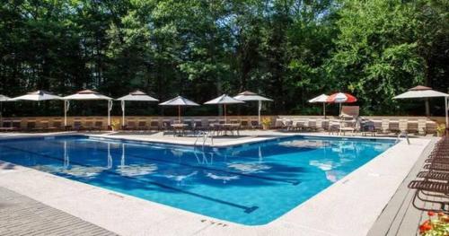 a large swimming pool with umbrellas and tables and chairs at L&R in Torrington