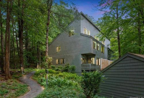 a gray house in the woods with a driveway at L&R in Torrington