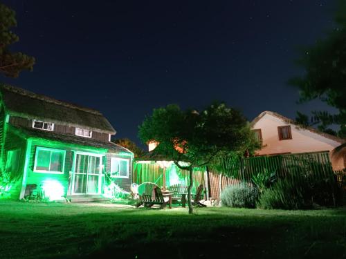 a house with green lights on a yard at night at Los diablitos in Punta Del Diablo