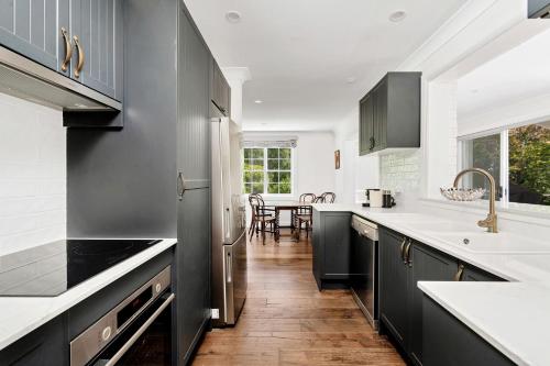a kitchen with black cabinets and white counter tops at Cherry Tree Cottage, Burrawang, Southern Highlands in Burrawang