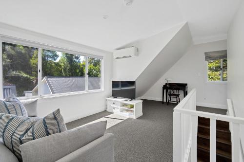 a white living room with a couch and a window at Cherry Tree Cottage, Burrawang, Southern Highlands in Burrawang
