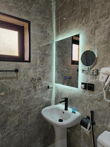 a bathroom with a sink and a mirror at قمة راحتي للشقق المخدومة Qimat Rahaity SERVICED APARTMENTS in Yanbu
