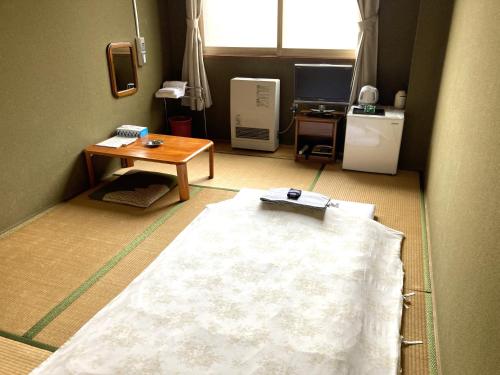 Habitación con mesa y alfombra blanca en el suelo en Hotel Tetora Yunokawaonsen, en Hakodate